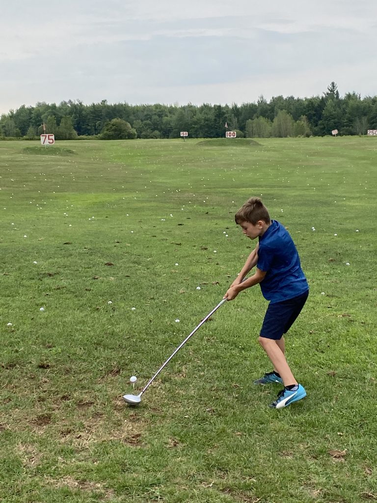 Camp de formation : un garçon avec un bois prêt à frapper sa balle de golf positionné sur un té